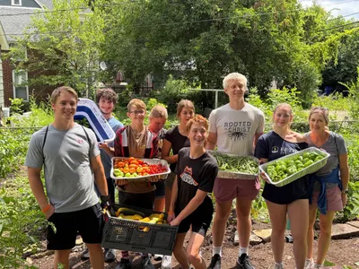 Students holding trays of fresh produce harvested at a community garden